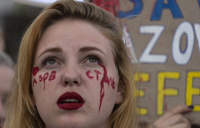 A relative with the writing ‘Above Steel’ on her face attends a rally in support of Ukrainian soldiers from the Azov Regiment who were captured by Russia in May after the fall of Mariupol, in Kyiv, Ukraine, Thursday, Aug. 4, 2022. The rally comes as U.S. officials believe Russia is working to fabricate evidence concerning last week’s deadly strike on a prison housing prisoners of war in a separatist region of eastern Ukraine. (AP Photo/Efrem Lukatsky) XEL104 XEL104