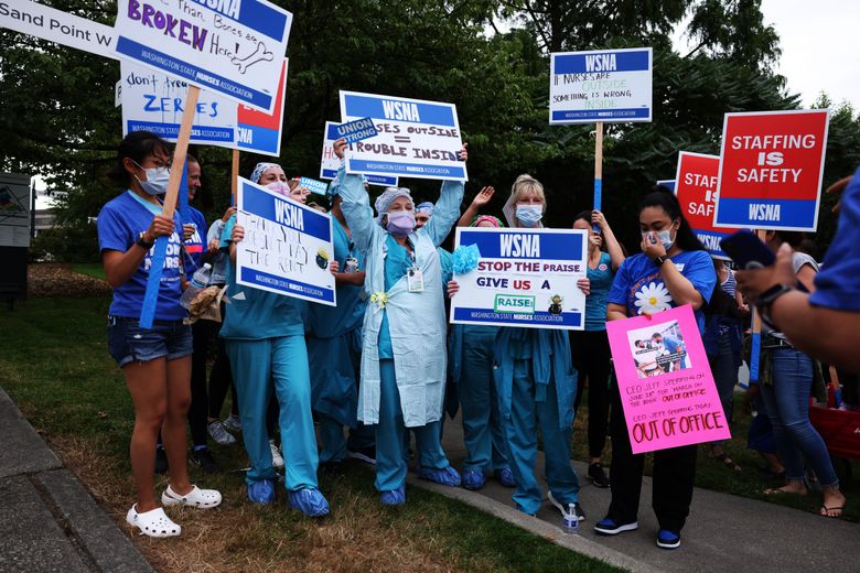 Operation room nurses and techs in scrubs hold signs together as they rally near the Seattle Children’s Hospital on Tuesday, Aug. 9, 2022.  (Daniel Kim / The Seattle Times)