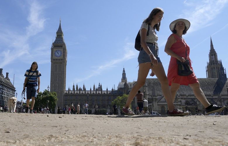 Tourists walk on the usually green grass covered Parliament square in London, Tuesday, Aug. 9, 2022. Britain is braced for another heatwave that will last longer than July’s record-breaking hot spell, with highs of up to 35C expected next week.( AP Photo/Frank Augstein) FAS109 FAS109