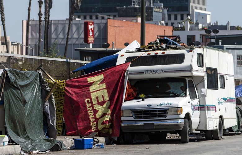 FILE – Homeless encampments block the street on an overpass of the Hollywood freeway in Los Angeles, in July 7, 2021. The Los Angeles City Council has voted to ban homeless encampments within 500 feet of schools and daycare centers. The council voted Tuesday, Aug. 9, 2022 to broaden an existing ban on sleeping or camping near the facilities. (AP Photo/Damian Dovarganes, File) LA202 LA202