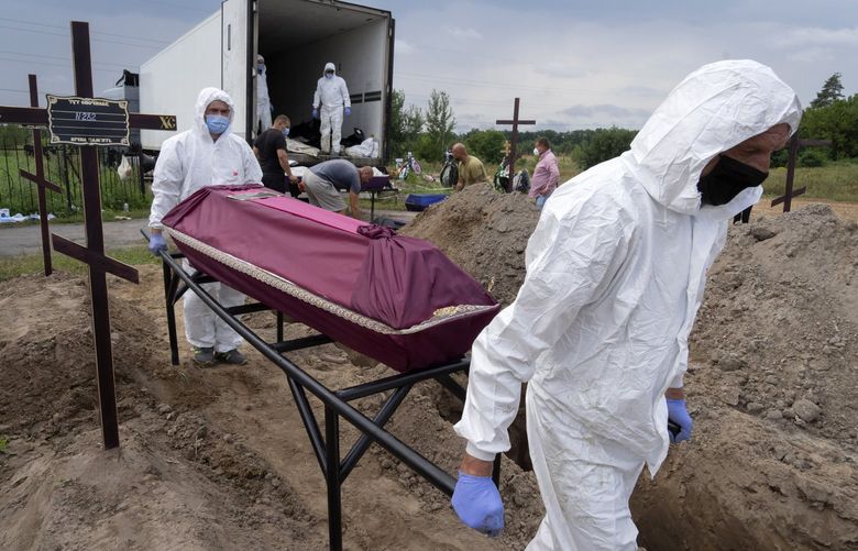 Workers carry a coffin with unidentified remains of a civilian murdered by the Russian troops during Russian occupation in Bucha, on the outskirts of Kyiv, Ukraine, Thursday, Aug. 11, 2022. Eleven unidentified bodies exhumed from a mass grave were buried in Bucha Thursday. (AP Photo/Efrem Lukatsky) XEL101 XEL101