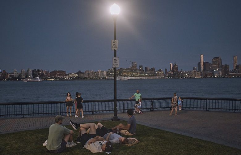 FILE – People spend time at the park at dusk during a summer heat wave, July 21, 2022, in Hoboken, N.J. The continental United States in July set a record for overnight warmth, providing little relief from the dayâ€™s sizzling heat for people, animals, plants and the electric grid, meteorologists said. (AP Photo/Andres Kudacki, File) CLI501 CLI501