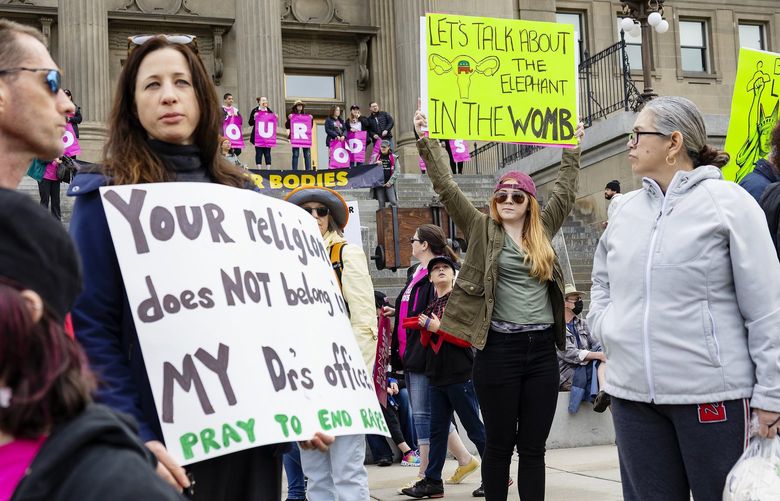 FILE – Boise resident Autumn Myers holds a sign with the Republican Party elephant symbol inside the outline of a uterus that reads, “Let’s talk about the elephant in the womb,” during a Planned Parenthood rally for abortion-rights at the Idaho Statehouse in downtown Boise, Saturday, May 14, 2022. On Friday, Aug. 12, 2022, the Idaho Supreme Court ruled that the state’s strict abortion bans will be allowed to take effect while legal challenges over the laws play out in court. (Sarah A. Miller/Idaho Statesman via AP, File) IDBOI502 IDBOI502