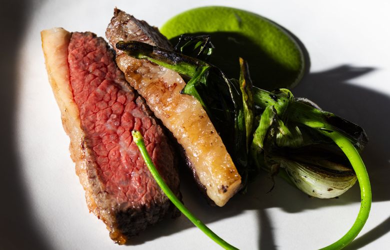The Wagyu beef from Enumclaw, WA with spring onions and a sauce made from pumpkin seeds at TOMO, Thursday, Aug. 11, 2022 in West Seattle’s White Center neighborhood. (Ken Lambert / The Seattle Times)