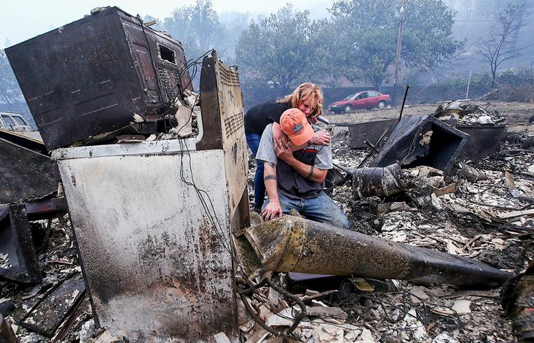 Sherri Marchetti-Perrault and James Benton embrace as they sift through the remains of their home near Yreka, California. (Luis Sinco/Los Angeles Times/TNS) 54765207W