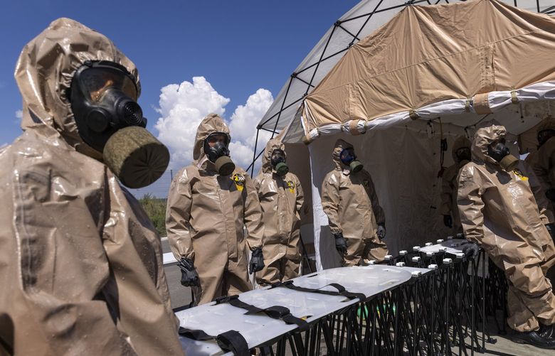Ukrainian emergency rescue teams, wearing suits to protect against radiation, practice a nuclear disaster drill in a parking lot, which has been used for months as a transit and registration point for Ukrainian evacuees fleeing Russian occupied territory, in Zaporizhzhia, Ukraine on Aug. 17, 2022. Ukrainian officials have said that the Russian military is using the occupied Zaporizhzhia Nuclear Power Station, the largest nuclear power plant in Europe and among the 10 largest in the world, as a base to launch attacks, raising broader security fears in surrounding areas. (David Guttenfelder/The New York Times). XNYT26 XNYT26