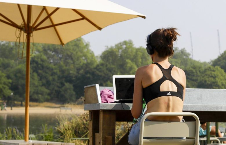 A woman uses a laptop outside at a cafe in Hyde Park in London, in 2020. (AP Photo / Kirsty Wigglesworth, file) 