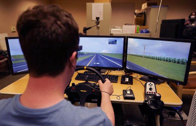 Tate Ellwood-Mielewski test drives on a simulator at the University of Michigan, Friday, April 29, 2022, in Ann Arbor, Mich. Michigan researchers plan to study how well those with autism spectrum disorder detect road hazards and assist the young motorists in sharpening their driving skills. The upcoming effort marks the second phase of a project that is funded by Ford Motor Co. and teams the Ann Arbor university with a local driving school. (AP Photo/Carlos Osorio) MICO201 MICO201