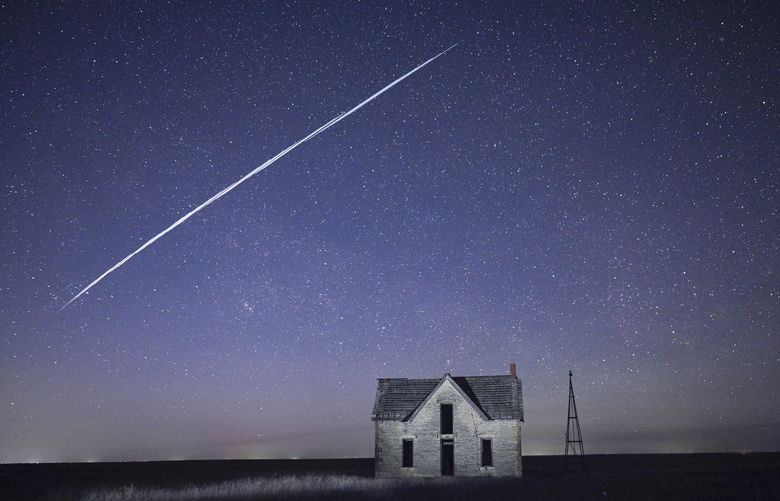 FILE – In this photo taken with a long exposure, a string of Elon Musk’s SpaceX StarLink satellites passes over an old stone house near Florence, Kan,  May 6, 2021.  (AP Photo/Reed Hoffmann, File) 