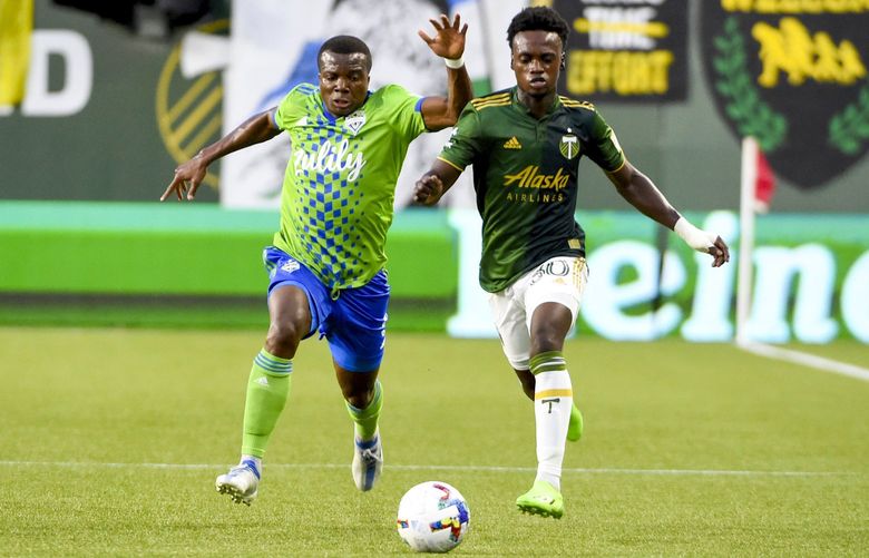 Seattle Sounders defender Nouhou Tolo, left, and Portland Timbers midfielder Santiago Moreno, right, go after a ball during the first half of an MLS soccer match in Portland, Ore., Friday, Aug. 26, 2022 (AP Photo/Steve Dykes) ORSD106