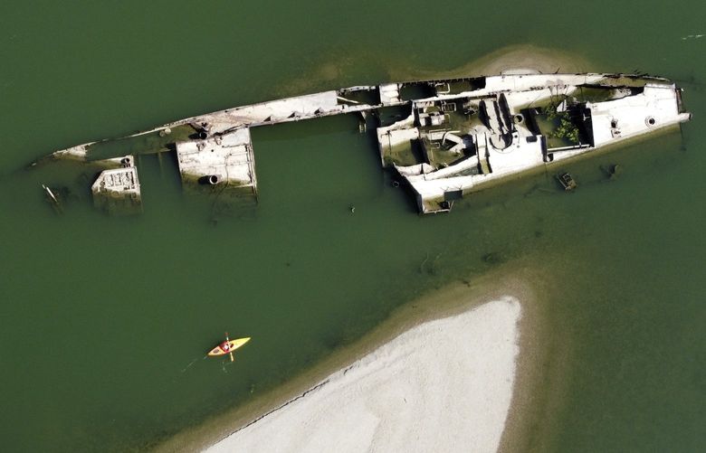 A kayaker paddles by the wreckage of a WWII German warship in the Danube river near Prahovo, Serbia, Friday, Aug. 26, 2022. The hulks of dozens of World War II German battle ships have been exposed on the Danube River in Serbia near the town of Prahovo after severe drought hit most of Europe this summer. The ships, some still laden with explosive munition, used to belong to Nazi Germany’s Black Sea fleet that was self-destroyed by Germans as it retreated from advancing Russian forces from Romania in 1944. The sunken ships often hamper river traffic on Europe’s second-largest river, especially in summer when water levels are low. There are plans to take those ships out of the river. (AP Photo/Darko Vojinovic) XDMV1 XDMV1