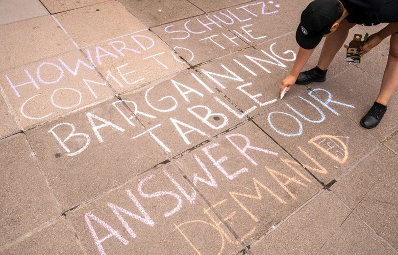 A demonstrator writes a message with chalk while protesting outside a closed Starbucks Corp. location at 505 Union Station in Seattle, Washington, US, on Saturday, July 16, 2022. Starbucks Workers United said it intends to file unfair labor practice charges against Starbucks on behalf of the two unionized stores that closed in Seattle. Starbucks insisted the closures weren’t related to the unionization drive but due to safety issues, reports the Associated Press. 775843338