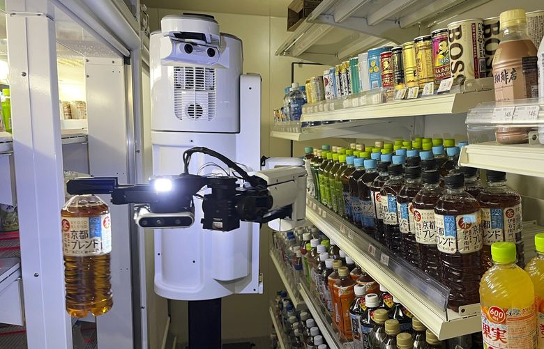 TX SCARA robot works, stocking drinks in the refrigerated section of a FamilyMart convenience store in Tokyo, Friday, Aug. 26, 2022. The robot can restock shelves with up to 1,000 bottles and cans a day. (AP Photo/Yuri Kageyama) 