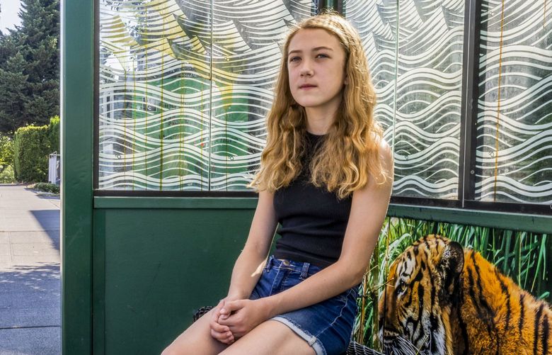 Addie Trask sits at a bus stop in Seattle on Wednesday, Aug. 31, 2022. Addie will be taking the metro bus to when school starts: “It removes a barrier that would have otherwise been a consideration in how we think about getting our kid to school maybe we would have opted to drive her more often…It gives her just another tool in her toolbox to get to school whether it’s walking or biking” said her father, Blake Trask.