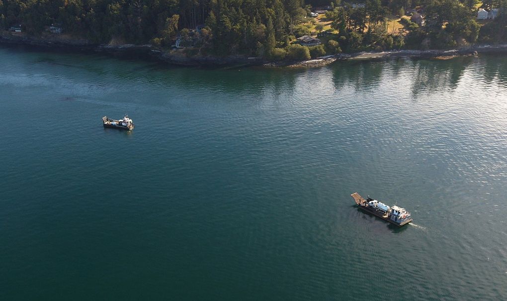 This aerial photo provided by the U.S. Coast Guard shows work underway Monday to mitigate environmental damage from a fishing boat that sank near San Juan Island on Sunday.