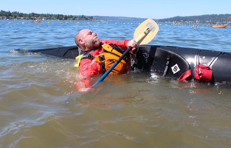 Seattle resident Patrick McMurchie goes from submerged to upright while practicing the kayak roll – a useful skill for sea kayaking — during a lesson on Lake Sammamish in July 2022.