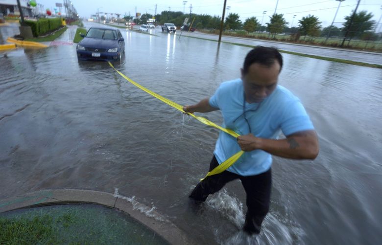 Mon Lun pulls a strap to his water stalled car before towing it out of receding flood waters in Dallas, Monday, Aug. 22, 2022. (AP Photo/LM Otero) TXMO101 TXMO101