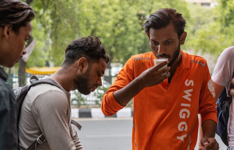 Mohammad Hussain takes a break from work for a quick bite at a roadside food cart in New Delhi. It’s difficult for him to get his water bottle refilled as often as he needs to. MUST CREDIT: Photo by Smita Sharma for The Washington Post.