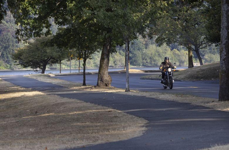 A motorcyclist cruises last week on Lakeside Avenue South, just south of the Lakewood Marina in Seattle. More unusually warm weather is expected as September winds down. (Ellen M. Banner / The Seattle Times)