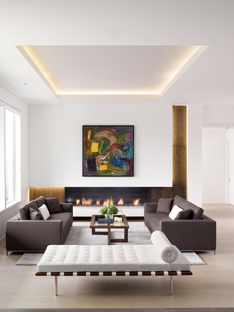Without a television as focal-point competition, an asymmetrical fireplace composition by Stuart Silk Architects takes center stage in the living room of a contemporary home on Mercer Island, while light strips highlight recessed bands of gold leaf. (Alex Hayden / Courtesy Stuart Silk Architects)