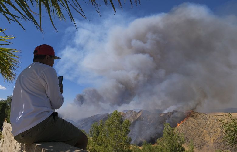 A man watches as smoke rises from a wildfire in Castaic, Calif., on Wednesday, Aug. 31, 2022. (AP Photo/Ringo H.W. Chiu) CARC101 CARC101