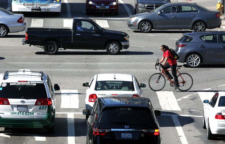 A cyclist maneuvers his way through downtown Los Angeles traffic on Tuesday, Sept. 16, 2014. California Gov. Jerry Brown announced Monday, Sept. 15, 2014 that he has signed legislation requiring California drivers to stay at least 3 feet away when passing bicyclists. The proposal is intended to better protect cyclists from aggressive drivers. It states that if drivers cannot leave 3 feet of space, they must slow down and pass only when it would not endanger the cyclist’s safety.  (AP Photo/Richard Vogel)