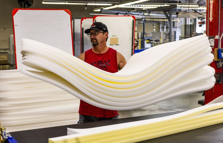 CNC operator Rick Nelson takes cut foam from the CNC machine and stacks it to be used for further manufacturing at the Therm-a-Rest factory in Seattle on Aug. 24, 2022.