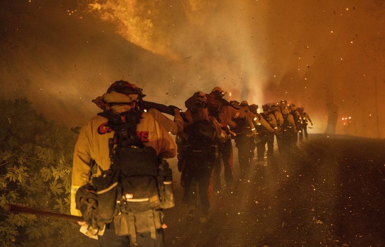 Cal Fire firefighters march through embers along Michigan Bluff road during the Mosquito Fire near Michigan Bluff in unincorporated Placer County, Calif. Wednesday, Sept. 7, 2022. (Stephen Lam/San Francisco Chronicle via AP) CAFRA501 CAFRA501