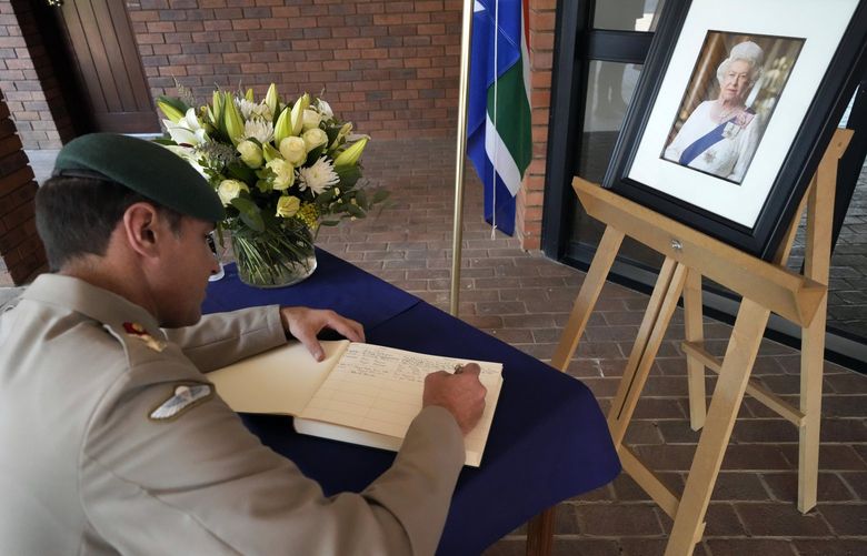 British Colonel Tristan Harris, signs a condolence book beside a picture of Queen Elizabeth II at the residence of British High Commissioner, at Waterkloof in Pretoria, South Africa, Friday, Sept. 9, 2022. Queen Elizabeth II, Britain’s longest-reigning monarch, died on Thursday Sept. 8, 2022 aged 96. (AP Photo/Themba Hadebe) XTH105 XTH105