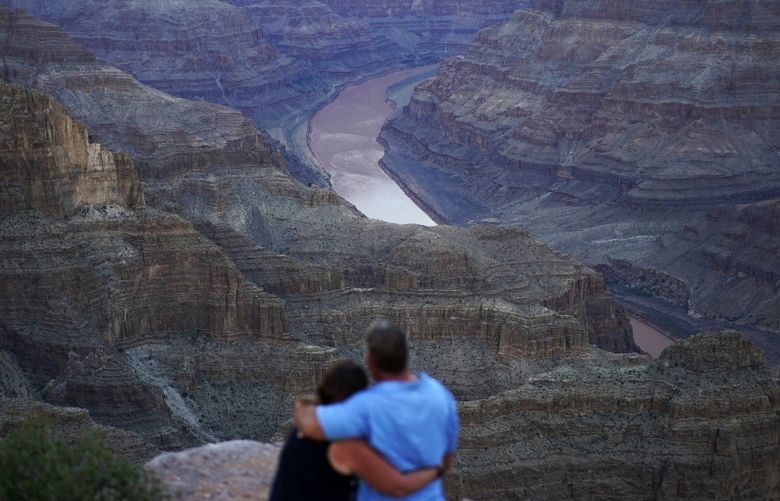 Alyssa Chubbuck, left, and Dan Bennett embrace while watching the sunset at Guano Point overlooking the Colorado River on the Hualapai reservation Monday, Aug. 15, 2022, in northwestern Arizona. In November 1922, seven land-owning white men brokered a deal to allocate water from the Colorado River, which winds through the West and ends in Mexico. During the past two decades, pressure has intensified on the river as the driest 22-year stretch in the past 1,200 years has gripped the southwestern U.S. (AP Photo/John Locher) CLI501 CLI501