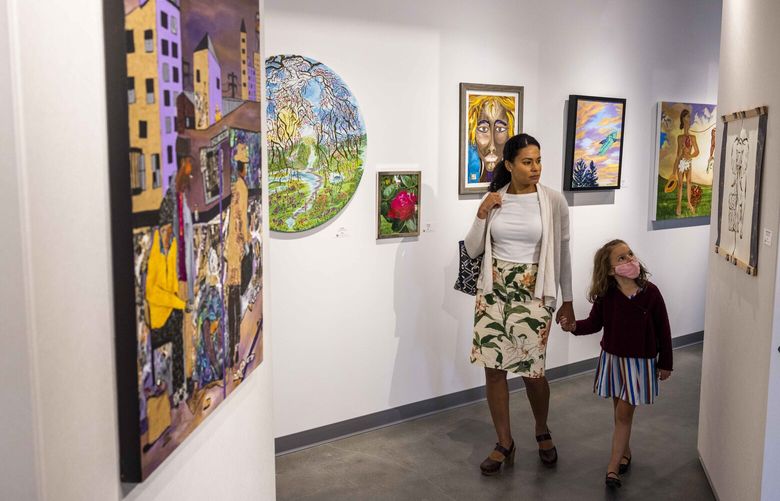 Melissa Mills, center, peruses the art pieces with her daughter Paloma, 6, at Gallery Onyx at Midtown Square at Arte Noir in the Central District on its opening day on Sept. 17, 2022. According to the Arte Noir website, Gallery Onyx is Seattle’s longest-running Black art gallery — its second location opened up at 23rd and Union on Saturday.