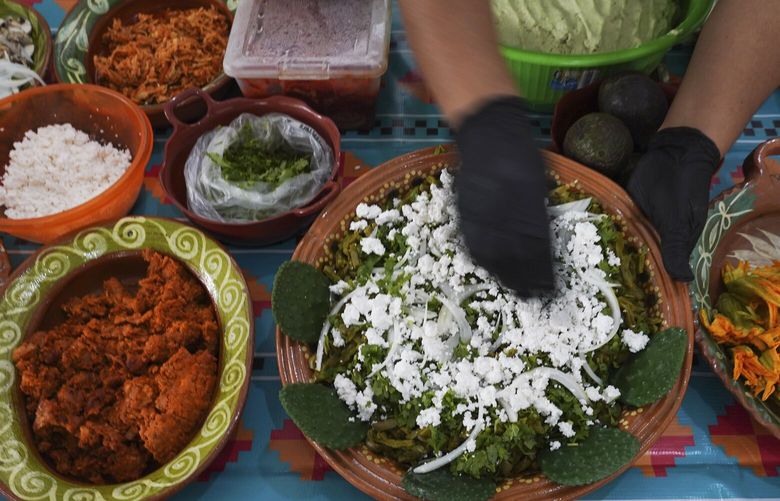 A vendor prepares a dish of nopales, cilantro and onions at the Pre-Hispanic Food Fair in the Iztapalapa borough of Mexico City, Friday, July 29, 2022. Iztapalapa, the largest borough in Mexico City, launched the fair to rescue and preserve traditional Mexican cuisine. (AP Photo/Marco Ugarte)