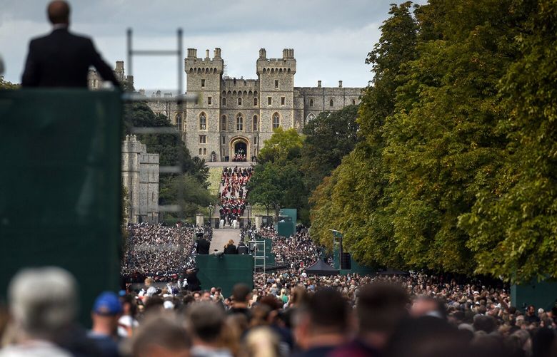 A throng of people watches as Queen Elizabeth II’s coffin arrives at Windsor Castle in Windsor, England, about 25 miles west of London, on Monday, Sept. 19, 2022. The queen’s coffin was lowered into the royal vault of St. George’s Chapel at Windsor Castle on Monday afternoon, signifying the end of a state funeral that began with a majestic service at Westminster Abbey, and a procession in London, before closing with a more intimate service at the place where the queen lived in the twilight years of her life. (Mary Turner / The New York Times)