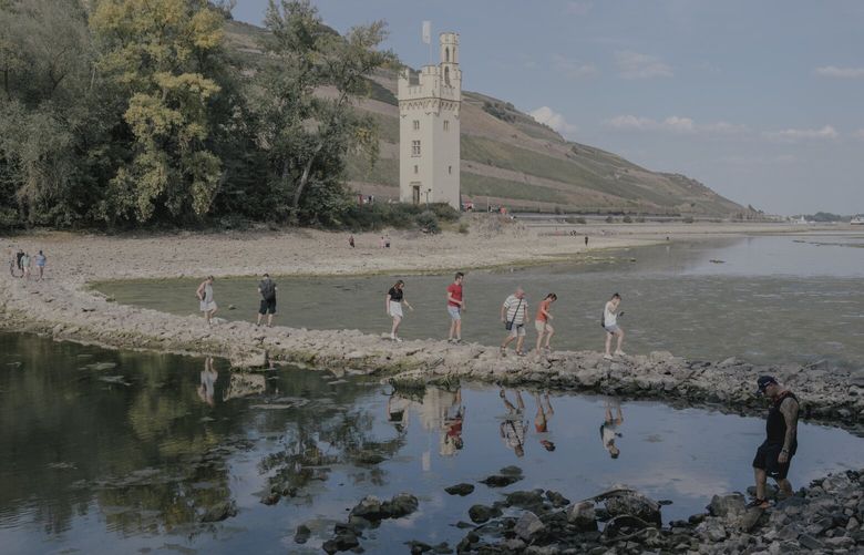 Tourists return on foot from a visit to MÃ¤useturm Island on the Rhine in Bingen, Germany on Aug. 14, 2022. Normally, the island can only be reached by boat, but due to the current low water levels on the river, it is accessible via a land bridge. (Ingmar BjÃ¶rn Nolting/The New York Times)