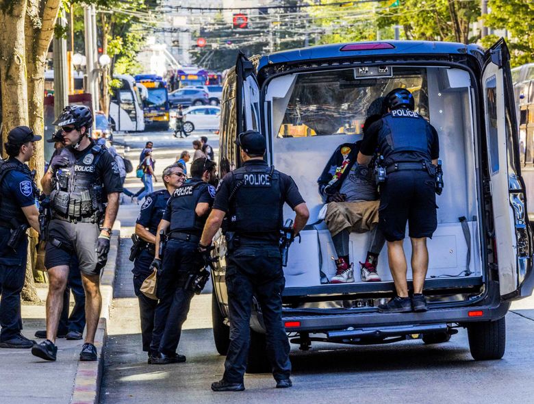 Seattle police detain a person suspected of distributing narcotics on Third Avenue. The busy area, a crossroads of tourist destinations, retail and public transit, has also been a trouble spot for drug dealing and other criminal activity. (Daniel Kim / The Seattle Times)