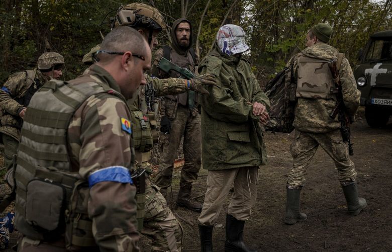 Ukrainian soldiers escort a captive, captured on the frontline and believed to be a spy for Russian forces, on to the west bank of the Siverskyi Donets River, near Lyman, Ukraine, on Tuesday, Sept. 27, 2022. Ukrainian forces recaptured the resort village of Szczurowe, on the eastern side of the Siverskyi Donets River, 10 days ago, and are attempting to recapture the town of Lyman from the south and western sides. (Nicole Tung/The New York Times) XNYT23 XNYT23