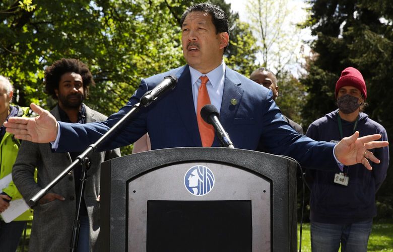 Seattle Mayor Bruce Harrell, center, speaks at a news conference Thursday, May 19, 2022, at Woodland Park in Seattle, where a homeless encampment was cleared. At left is Marc Dones, director of King County Regional Homelessness Authority.