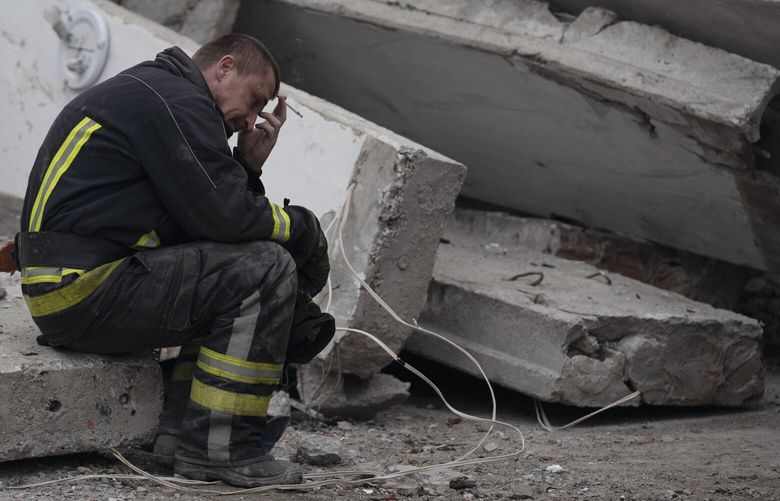 A rescue worker takes a pause as he sits on the debris at the scene where a woman was found dead after a Russian attack that heavily damaged a school in Mykolaivka, Ukraine, Wednesday, Sept. 28, 2022. (AP Photo/Leo Correa) XLC113 XLC113