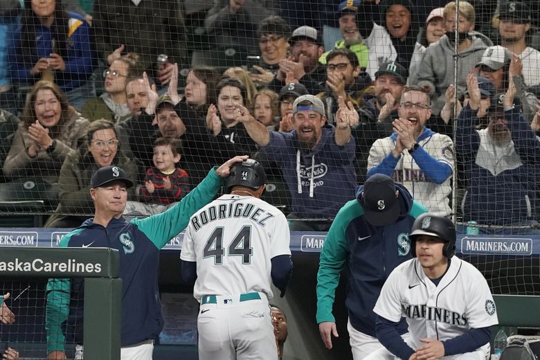 Fans cheer as Seattle Mariners’ Julio Rodriguez is greeted in the dugout by manager Scott Servais, left, after Rodriguez scored on an RBI-single hit by Mariners’ J.P. Crawford, May 28, 2022, in Seattle. (Ted S. Warren / The Associated Press)
