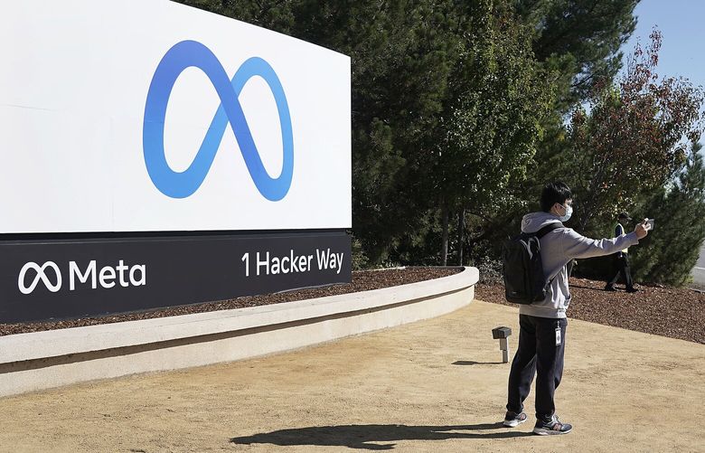 A Facebook employee take a selfie in front the company’s new name and logo outside its headquarters in Menlo Park, Calif., Thursday, Oct. 28, 2021, after announcing that it is changing its name to Meta Platforms Inc. (AP Photo/Tony Avelar) 
