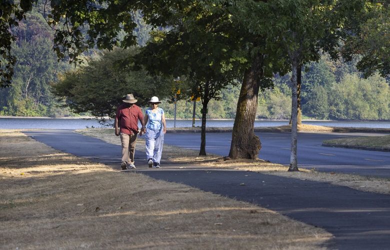 A couple walks down a path adjacent to Lakeside Ave. S. just south of the Lakewood Marina in Seattle Thursday, September 15, 2022.  There is a 30% chance of rain Friday, but skies should be sunny and in the mid 60’s to low 70’s through the middle of next week. 221600