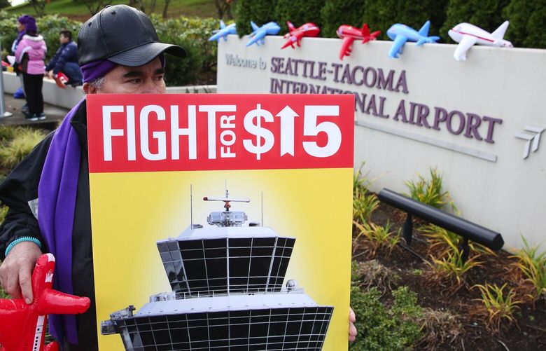 A man who said he does janitor work in Seattle, and didn’t want to give his name, is part of a $15 minimum wage protest outside Sea-Tac Airport, Tuesday, Nov. 28, 2016, in Seattle. Workers in Seattle already won $15 an hour, so it is more of a protest to unionize airport workers who aren’t.