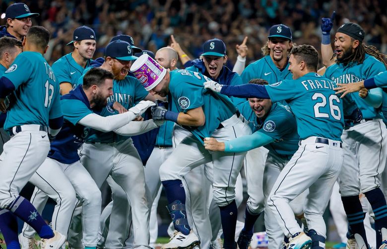 Teammates swarm Seattle Mariners catcher Cal Raleigh after Raleigh hit a walk-off home run to beat the Oakland Athletics 2-1 and secure the Mariners first post season berth in 21 years. 221659