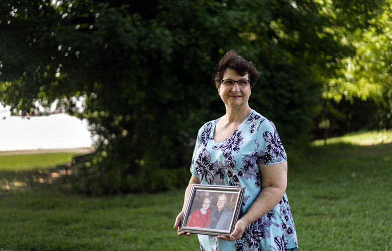 Dana Guthrie holds a portrait of her parents in Elizabethtown, Ky., on Aug. 27, 2022. Many employees reduce their hours or stop working to help ailing family members, but it may be years before they fully return to the work force, studies indicate. (Natosha Via/The New York Times)