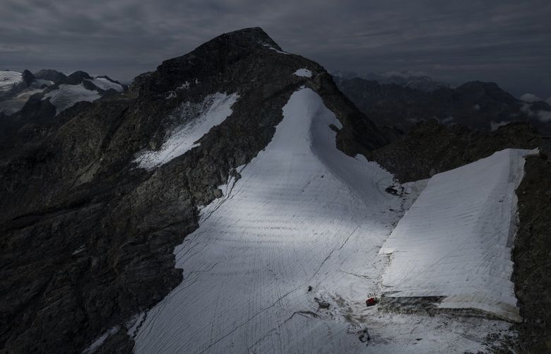 FILE –Parts of the ice of the Corvatsch glacier are covered with a tarpaulin, near Samedan, Switzerland, Monday, Sept. 5, 2022. Glaciologists have stopped their program to measure the glacier. The decision has already been taken in 2019 and the hot summer of 2022 has led to “extreme losses of ice” and the end of the program. The covered part of the glacier is used as a ski slope in winter. (Gian Ehrenzeller/Keystone via AP,file) PRO144 PRO144