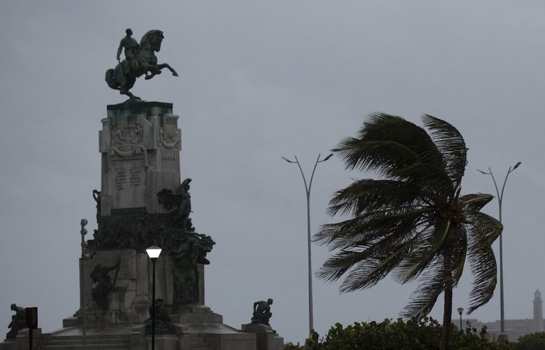 Wind blows a palm tree at the Antonio Maceo Monument along the malecon sea wall during the passing of Hurricane Ian in Havana, Cuba, early Thursday, Sept. 27, 2022. (AP Photo/Ismael Francisco) XIF102 XIF102