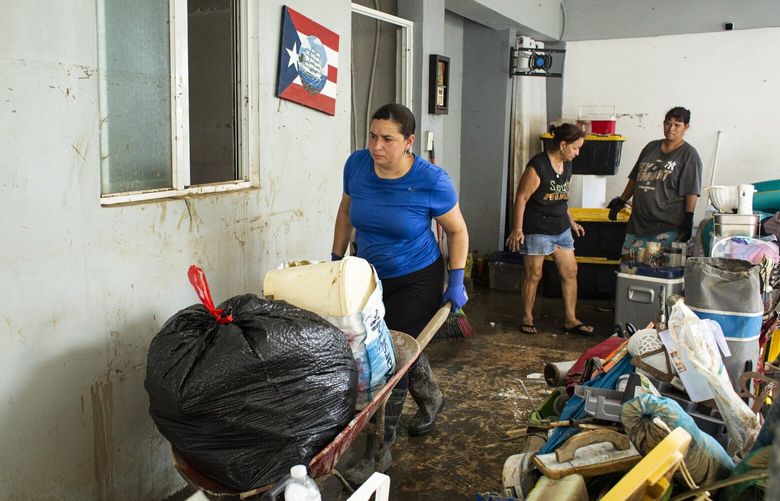 With the help of her family, MarÃ­a CortÃ©s DÃ(degrees)vila cleans her home after Hurricane Fiona dumped rain on Toa Baja, Puerto Rico on Sept. 20, 2022. Neighbors, who learned from Hurricane Maria not to wait for official help, are moving ruined appliances and, with brooms and shovels, wiping away the mud that coats their homes after Hurricane Fiona tore across the island this week. (Erika P. Rodriguez/The New York Times) XNYT274 XNYT274