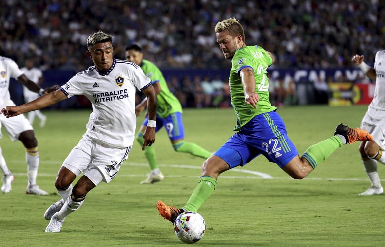 Seattle Sounders midfielder Kelyn Rowe, right, takes a shot against LA Galaxy defender Julian Araujo, left, during the first half of an MLS soccer match Friday, Aug. 19, 2022, in Carson, Calif. (AP Photo/Raul Romero Jr.) CARR105 CARR105
