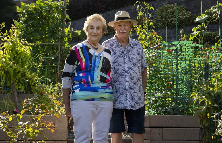 Charles and Louise Angel Kiss in the pea patch of their retirement community in Issaquah, Wash., Sept. 2, 2022. They weren’t able to sell their old home until they spent thousands of dollars renovating it. (Ruth Fremson / The New York Times)