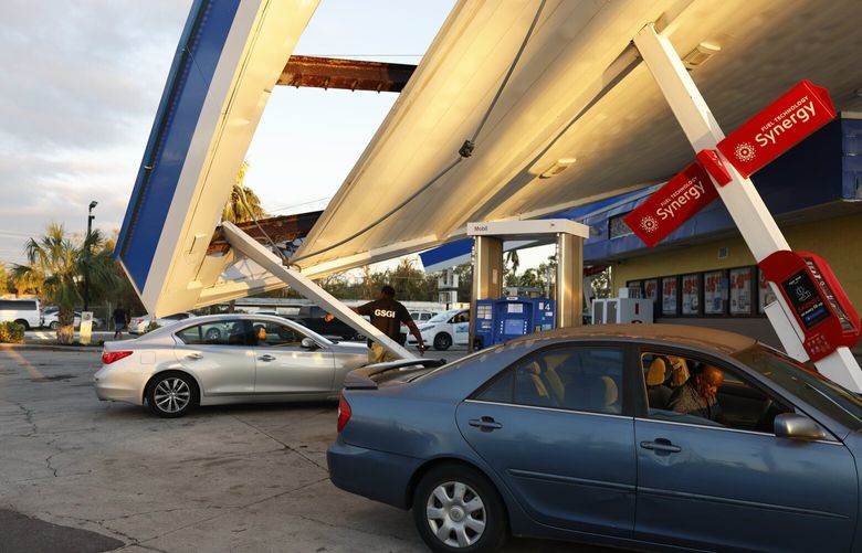 The roof of a Mobil gas station was destroyed, but it remains open for business in Fort Myers, Fla. on Sept. 30, 2022. The station re-opened the day prior after Hurricane Ian tore through the region, and it has been taking people, on average, two hours to fill their tanks. (Jason Andrew/The New York Times) XNYT15 XNYT15